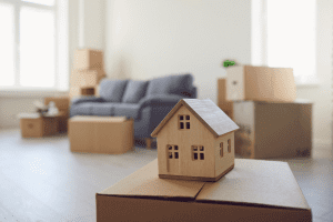 Miniature wooden house on cardboard boxes in a living room, representing apartment rentals in Eskişehir