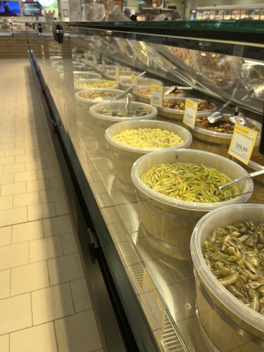 Deli counter at the Özdilek Hypermarket in Eskişehir, featuring large buckets of traditional Turkish pickles (turşu), green peppers, corn, and olives sold by weight.