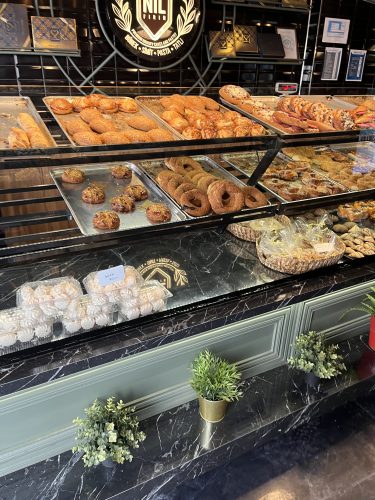 Glass display counter at Nil Fırın in Eskişehir, filled with trays of fresh Simit (sesame bagels), golden Poğaça (savory buns), and packaged Beze (meringues) under the bakery's logo.